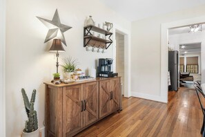 A kitchen with a wooden cabinet, a coffee maker, and a star decoration on the wall. - Cypress Star on the Medina | 4BR with Pool & River (Bandera)