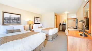 A hotel room with two beds, a desk with a lamp, a mirror, and a view of a lake.