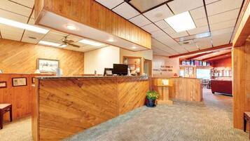 A reception area with wooden paneling, a reception desk, a television, and a potted plant.
