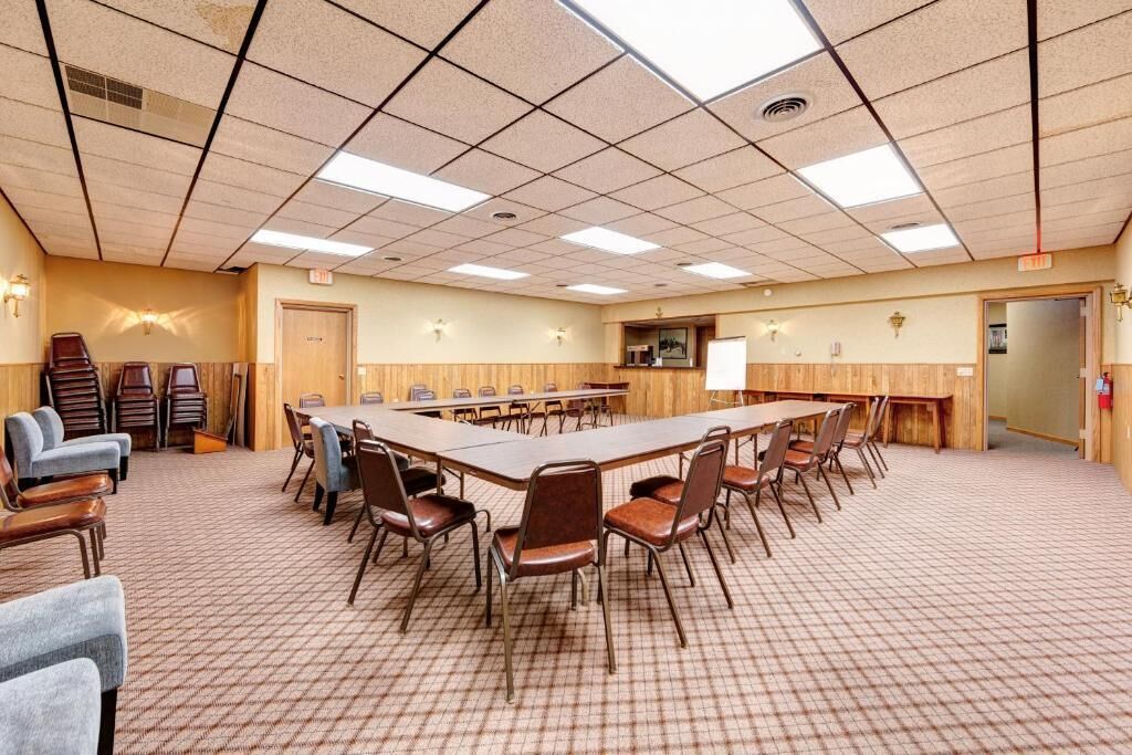 Una sala conferenze con un grande tavolo, sedie e pavimento rivestito di moquette.