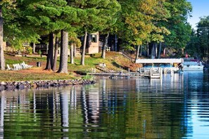 Una proprietà sul lago con un molo, una zona relax coperta e un edificio con tetto spiovente.