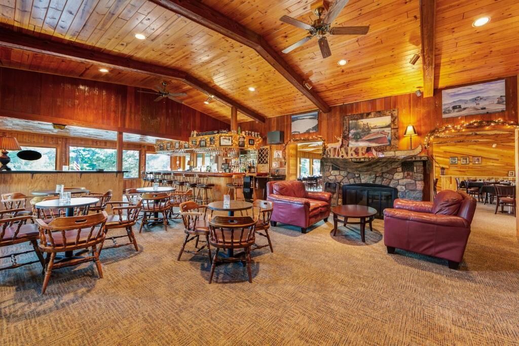 A cozy lodge with wooden interiors, a bar area, and a stone fireplace.