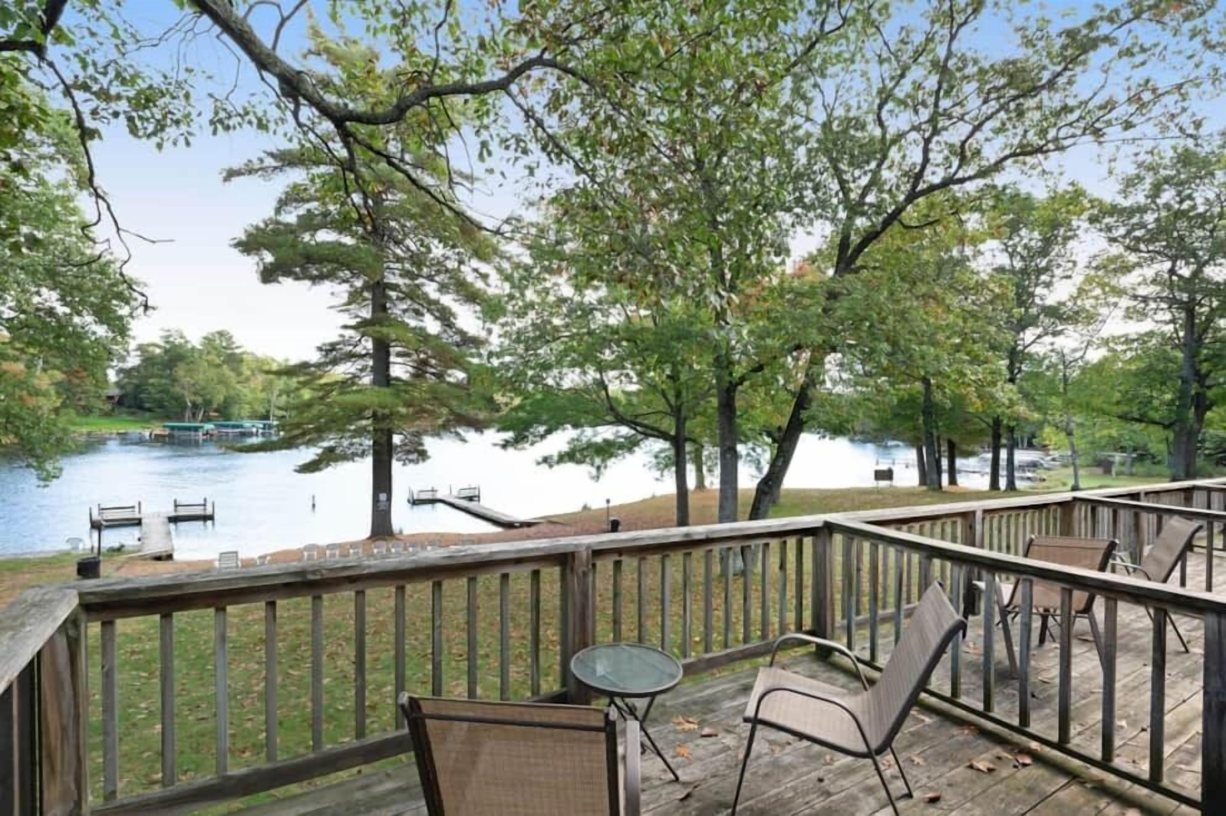 Una terraza de madera con mobiliario exterior con vistas a un lago.