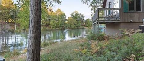 Una baita sul lago con un molo che si protende nell'acqua, circondata da alberi e vegetazione.