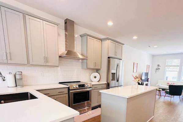 A modern kitchen with white cabinetry, stainless steel appliances, and a central island.