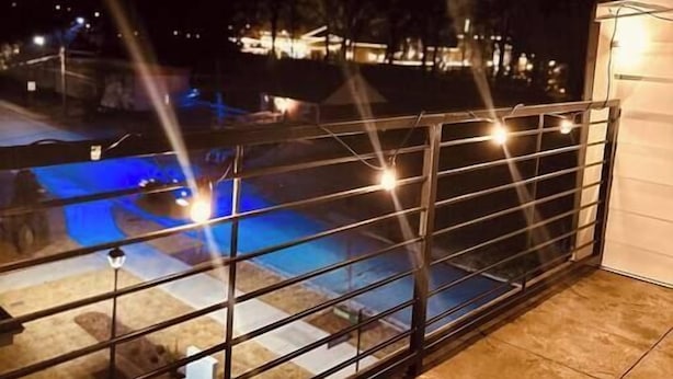 A pool area with a glass railing, a small building, and trees in the background. - Modern LoSo Retreat|Walk to Breweries & Light Rail (Charlotte)
