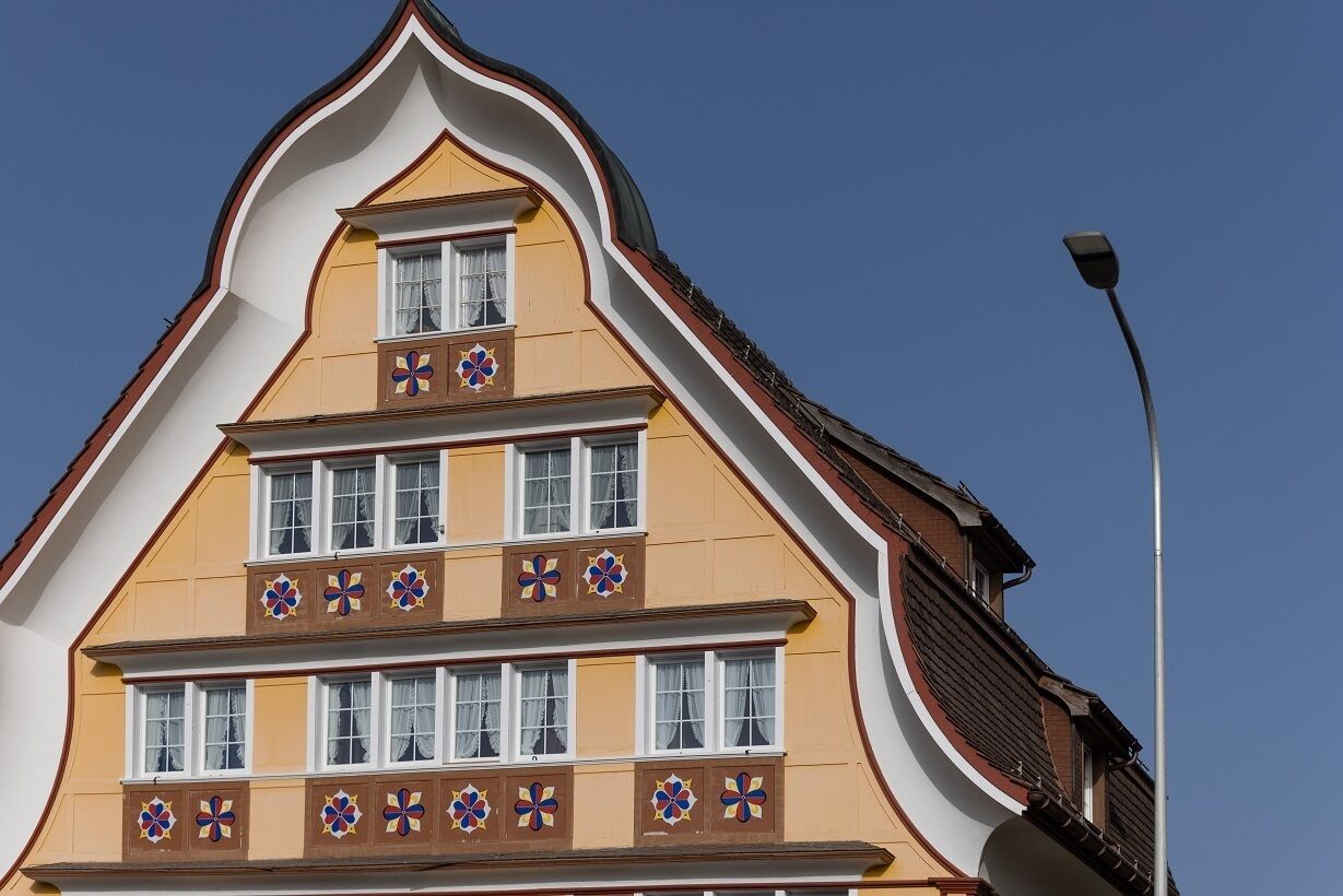 A multi-story building with a steeply pitched roof and decorative flower patterns on the facade.