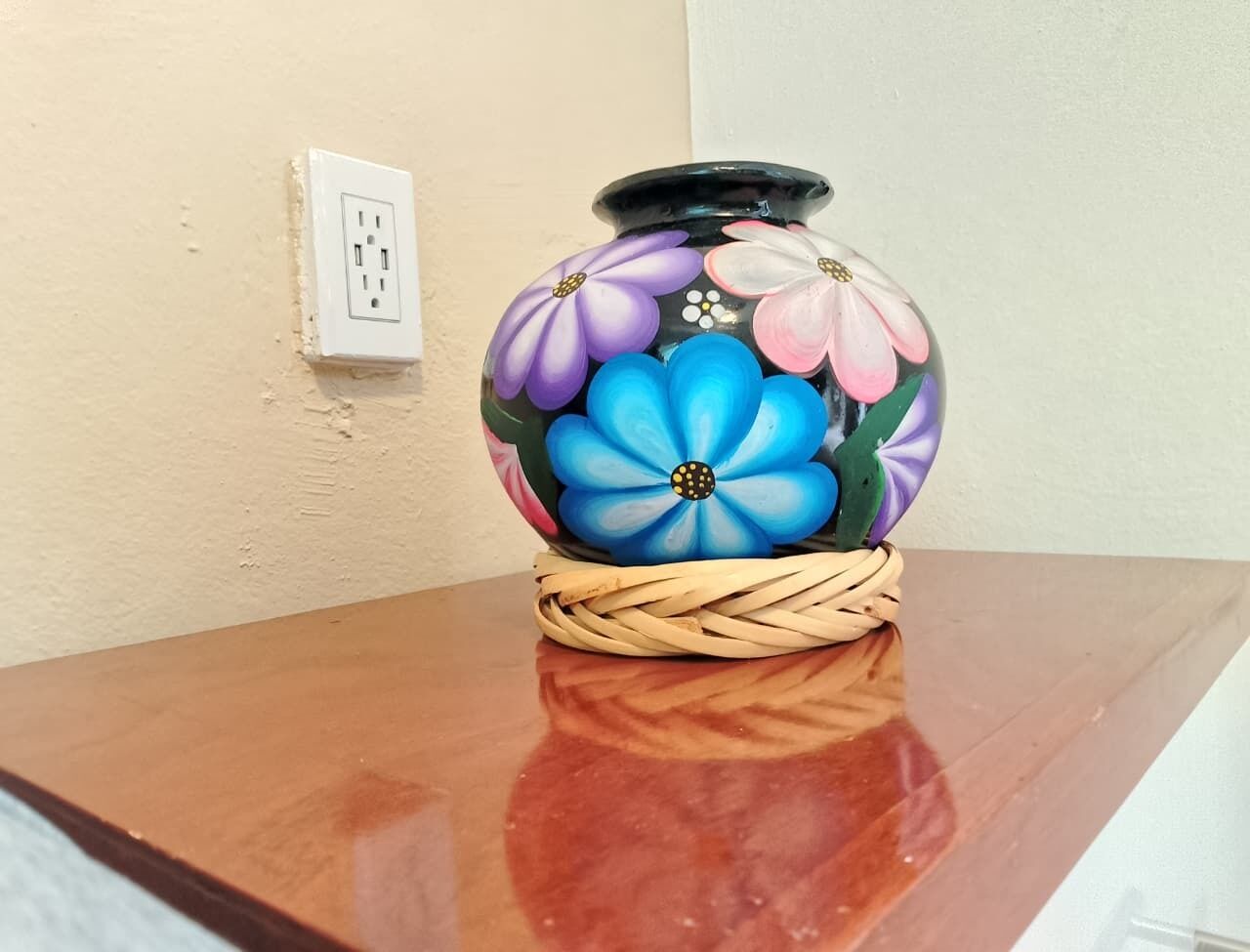 A vase with floral designs on a wooden table.