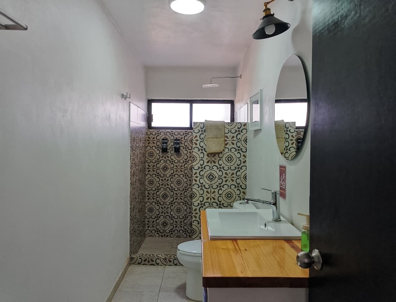 Ein Badezimmer mit Dusche, Toilette und Waschbecken, ausgestattet mit gemusterten Fliesen und einer Holz-Kommode.