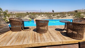 Une terrasse en bois avec des meubles en osier et une piscine.