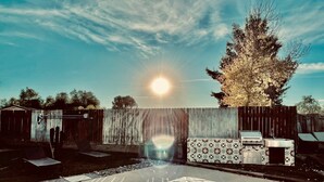 Un patio trasero con piscina, asador y valla de madera.