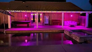 Un espacio al aire libre techado con piscina, asientos y una máquina expendedora.