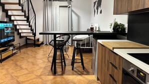 A modern kitchen with a wooden staircase, a dining area with two chairs, and a kitchen island. - Maisonette Near Beach & City Center (Heraklion)