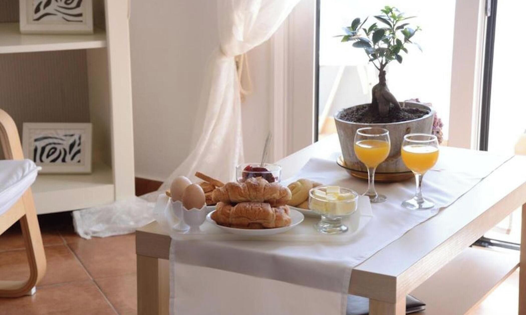 Une table de petit-déjeuner avec des croissants, des œufs et du jus d’orange.