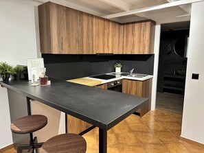A modern kitchen with wooden cabinets, a black countertop, and two stools.