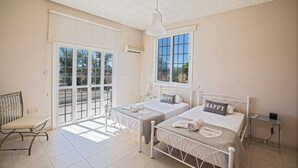 A bedroom with two beds, a bench, a window, and an air conditioning unit. - Papas Family Villa With Private Pool Wheelchair Accessible (Paralimni)
