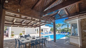 An outdoor dining area with a pool and lounge chairs. - Papas Family Villa With Private Pool Wheelchair Accessible (Paralimni)