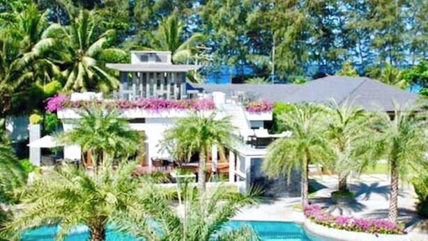 A resort with a pool, palm trees, and a building with a balcony.
