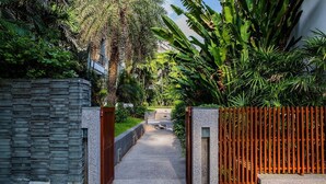 A pathway flanked by a stone wall and a wooden fence, leading to a building.