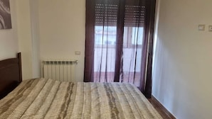 Ein Schlafzimmer mit einem Bett, einem Heizkörper und einem Fenster mit Vorhängen.