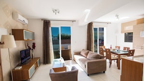 Una sala de estar moderna con un sofá, televisión y comedor.