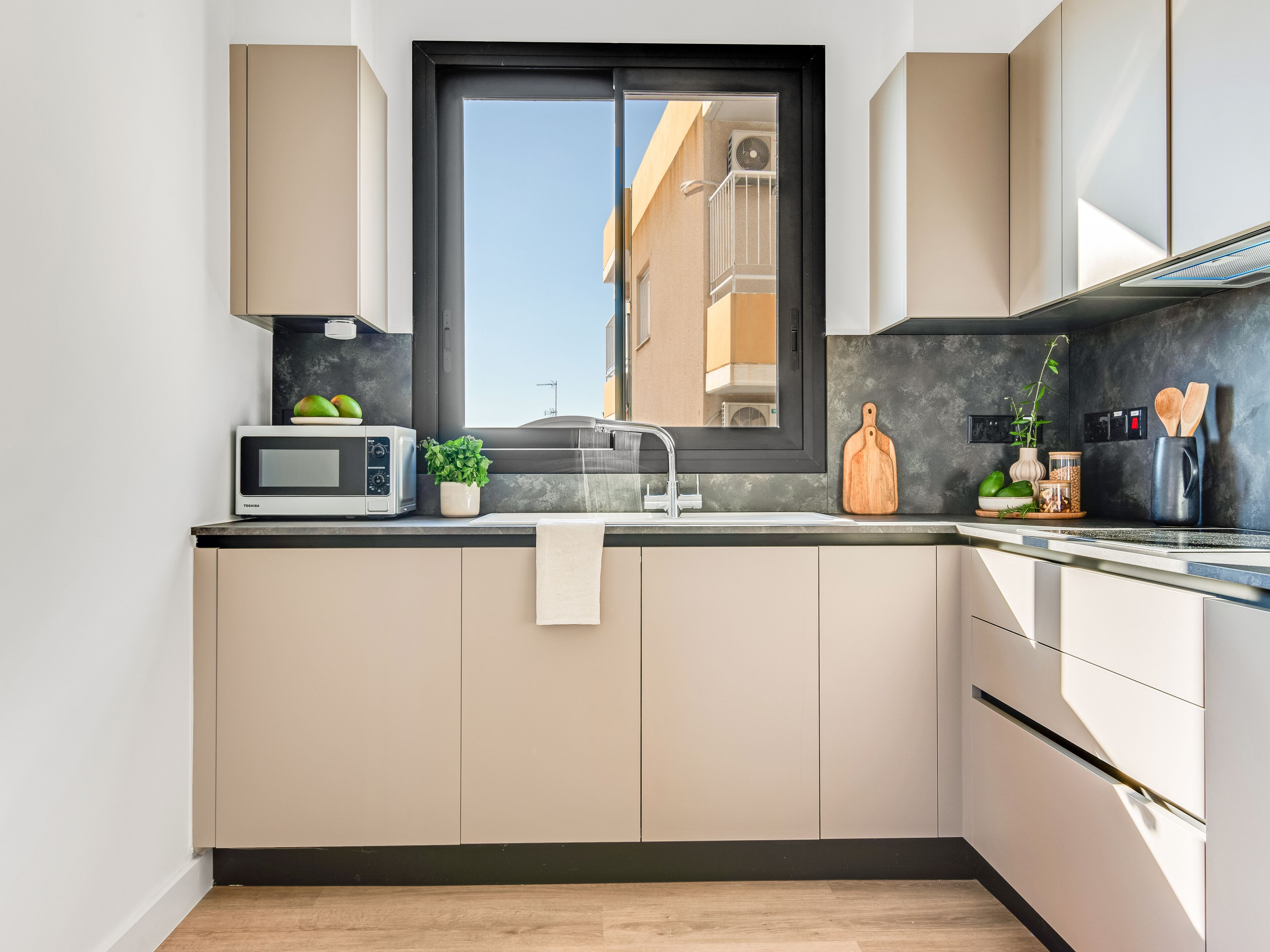 A modern kitchen with a built-in microwave, a sink, and a window.
