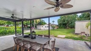 A covered patio with a dining table and chairs, a ceiling fan, and a view of the backyard. - Group-Friendly Home | Patio & Parking for 5 (Miami)