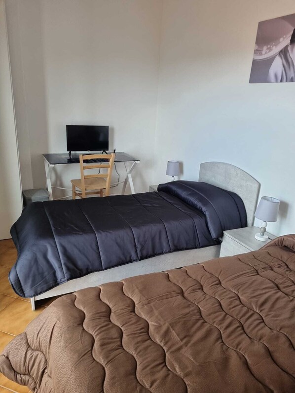 Un dormitorio con una cama, un escritorio con computadora y una silla.