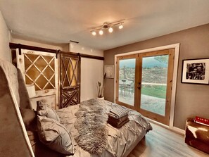 A bedroom with a bed, a window with a view, a ceiling fan, and a door with a decorative design. - Love Casa Pool Fire Pit Close To Wineries (Temecula)