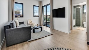 A modern living room with a grey sofa, a coffee table, and a TV mounted on the wall. - Sanders Crystal 2 - Cute 1-bdr Apt With Shared Rooftop (Limassol)