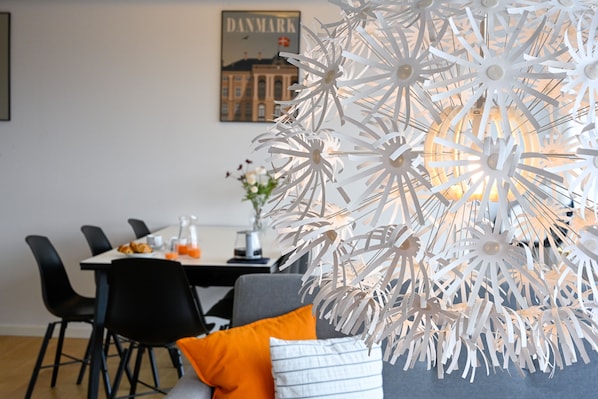 A dining area with a white paper art installation, a table with chairs, and a framed picture on the wall.