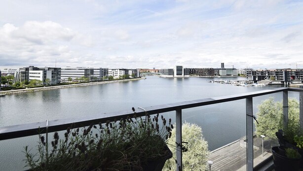 A river view from a balcony with modern buildings and a marina in the background. - Modern Apartment in Copenhagen Sluseholmen With a Marvellous View (Copenhagen)