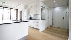 A modern kitchen with white cabinets, a black countertop, and a large window. - Modern Apartment in Copenhagen Sluseholmen With a Marvellous View (Copenhagen)