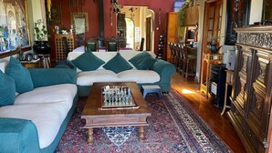 A cozy living room with a large sofa, a coffee table with chess pieces, and a patterned rug. - Room-living In Camps Bay Blue (Cape Town)