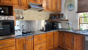 A kitchen with wooden cabinets, a stainless steel oven, a microwave, and a coffee maker. - Room-living In Camps Bay Blue (Cape Town)