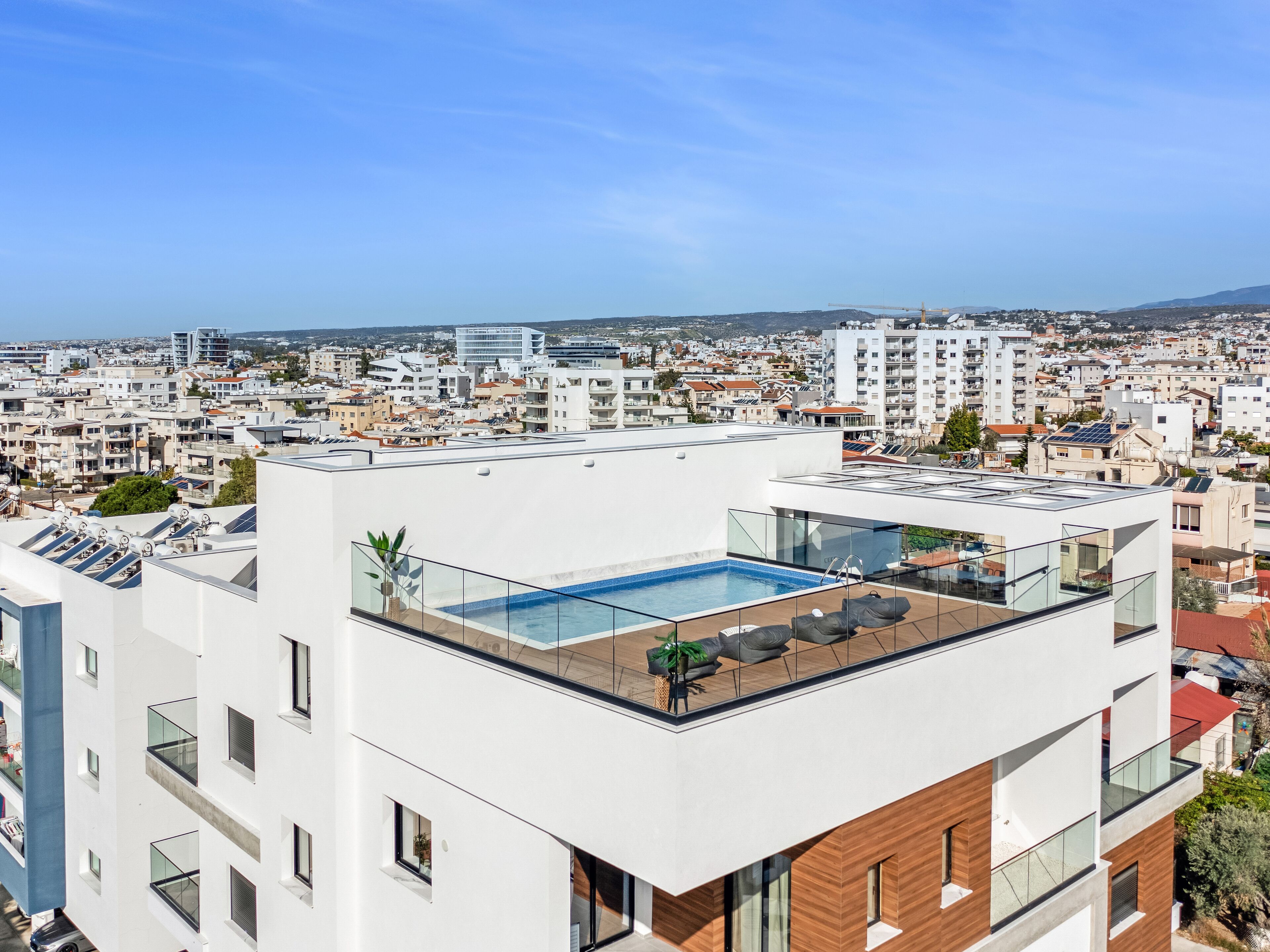 Un edificio moderno con piscina sul tetto, ampie finestre e vista sulla città.