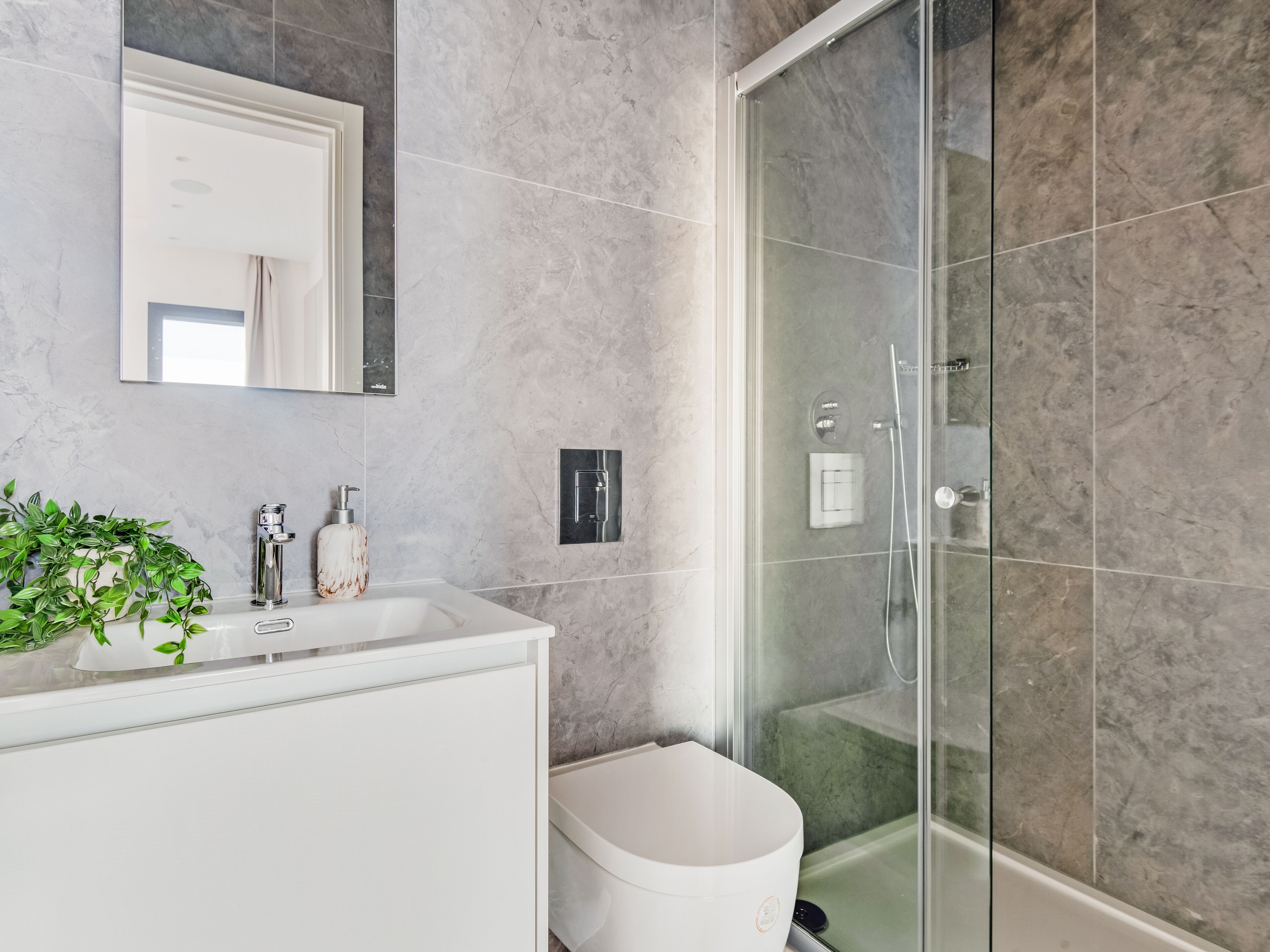 Une salle de bain moderne avec un meuble-lavabo blanc, une cabine de douche en verre et un pare-baignoire en marbre.