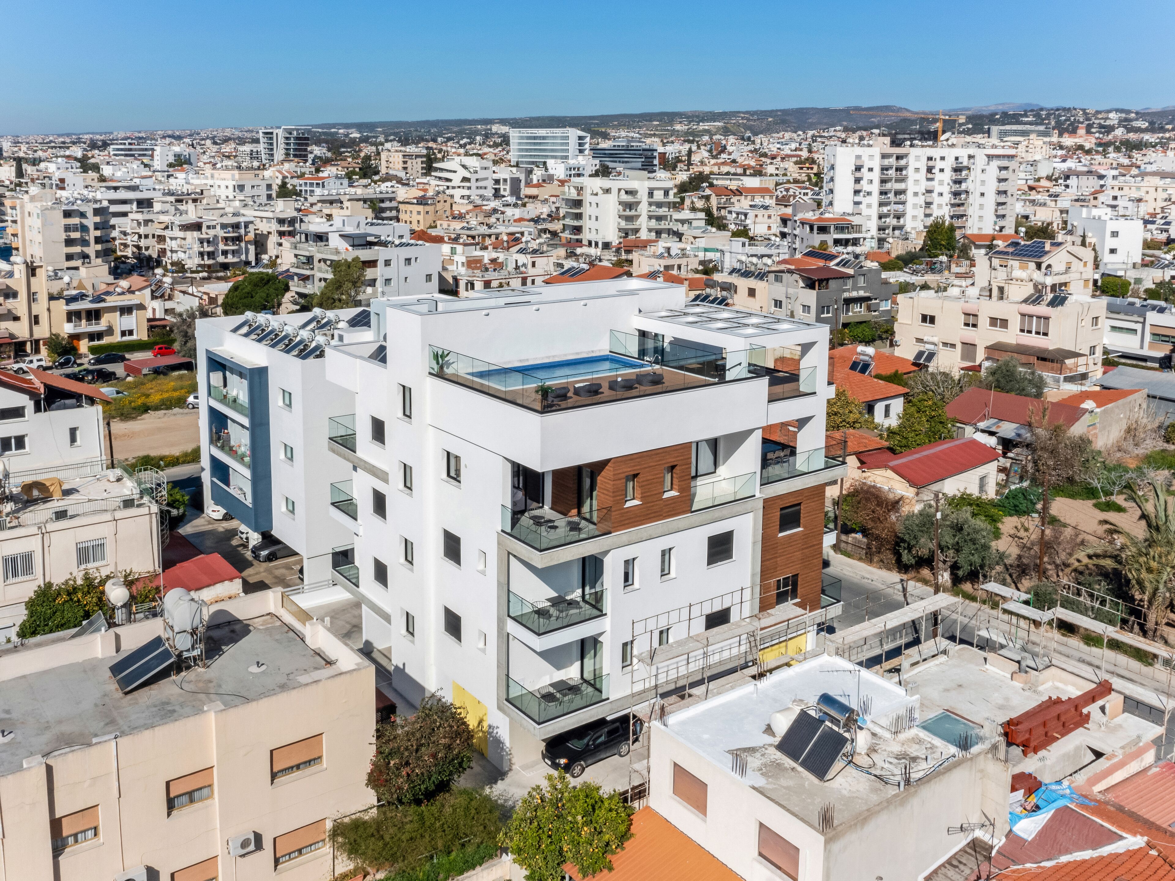 A modern multi-story building with a rooftop pool and glass balconies.