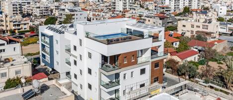 A modern multi-story building with a rooftop pool and glass balconies.