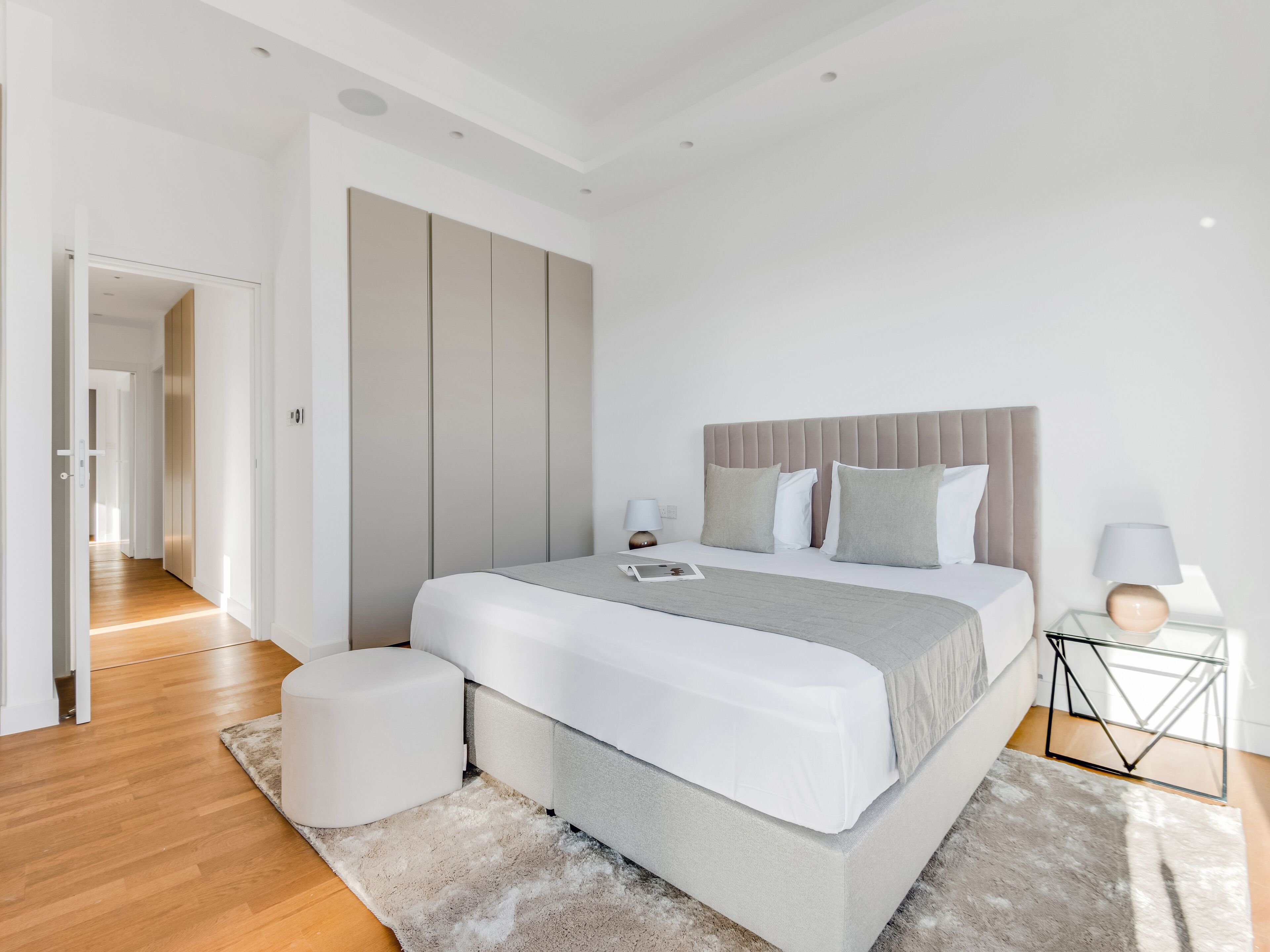 Ein modernes Schlafzimmer mit einem großen Bett, einem Nachttisch, einem Beistelltisch und einem begehbaren Kleiderschrank.
