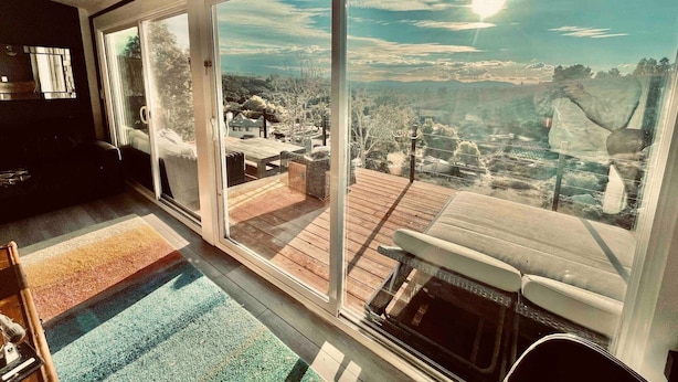 A room with large sliding glass doors leading to a deck with a view of a town and hills. - Mountain View Ranch Pool Hot Tub 15guests (Temecula)
