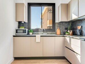 Een moderne keuken met een ingebouwde magnetron, een spoelbak en een raam.