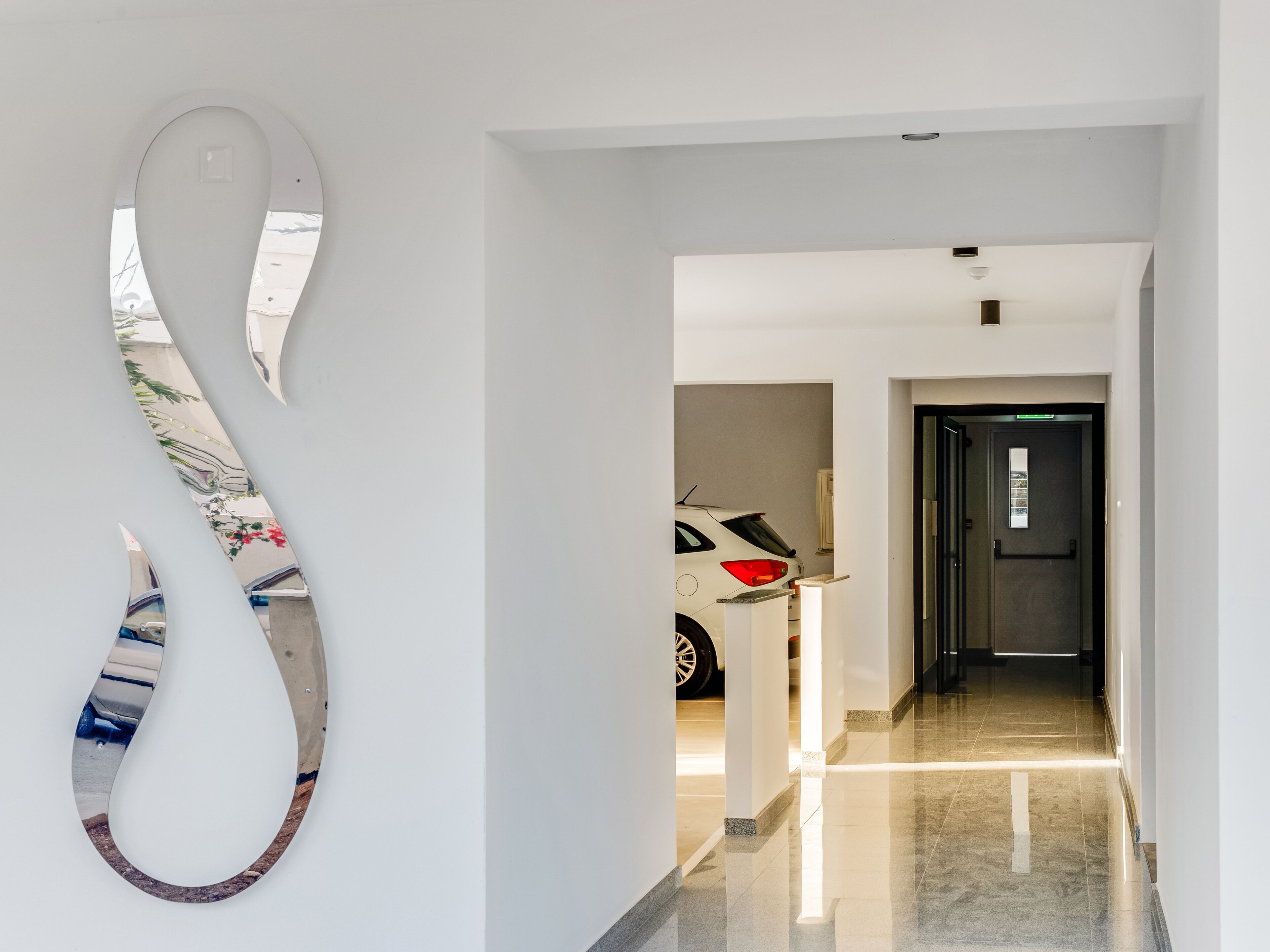 A hallway with a modern, minimalist design, featuring a large, abstract wall art piece and a sleek, contemporary door.