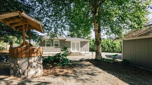 Una casa con base de piedra, una pérgola de madera y un jardín bien cuidado.