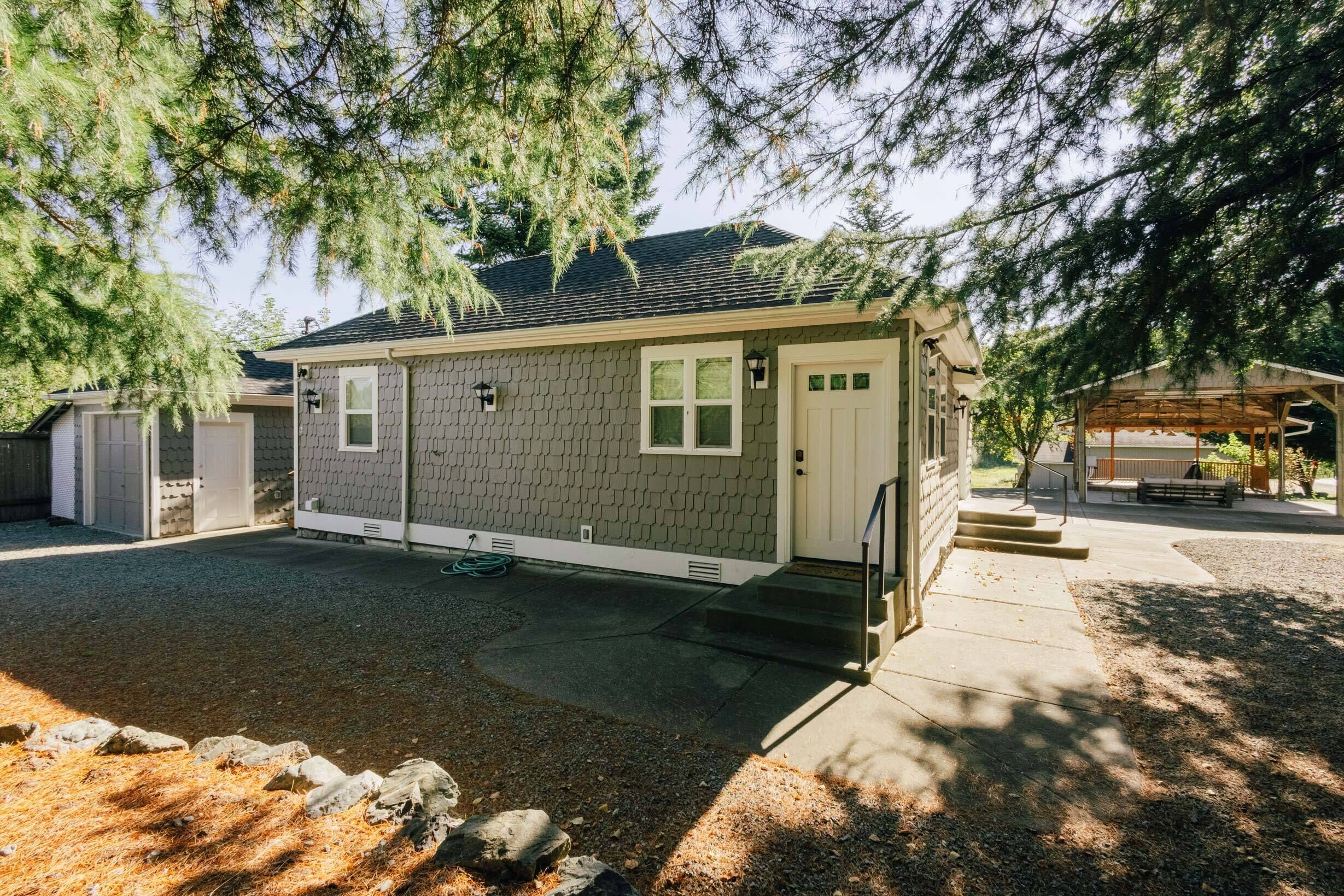 A single-story house with a gray exterior, a front door, and a covered porch area.