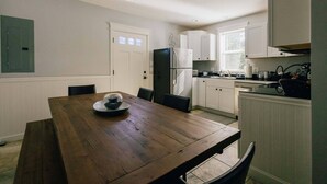 Una cocina moderna con armarios blancos, un refrigerador negro y una mesa de comedor de madera con sillas.