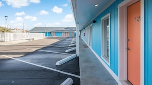 Um motel com uma fileira de quartos, fachada azul e portas laranjas, numerados em sequência.