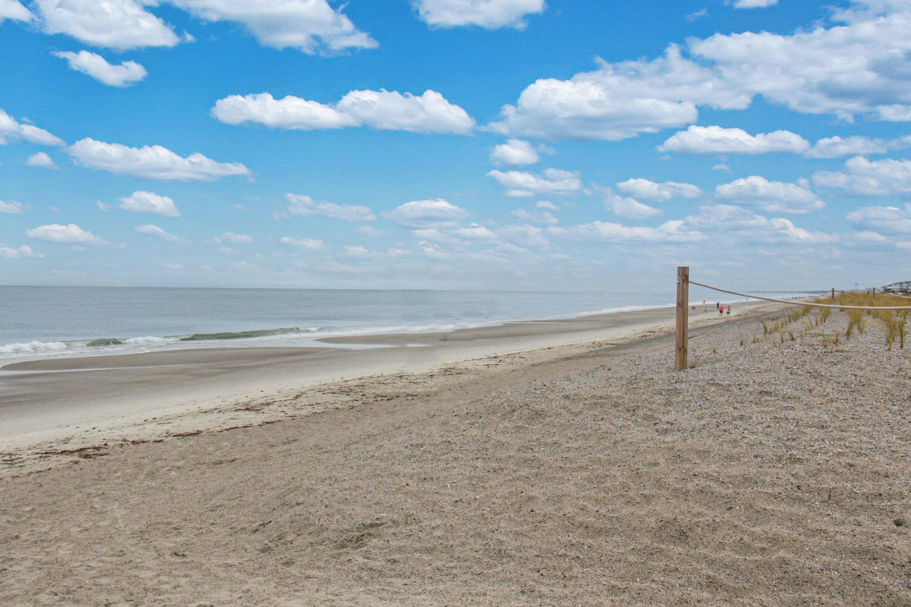 A beach with a wooden swing set and a rope barrier.