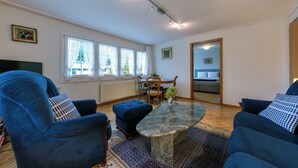 Ein geräumiges Wohnzimmer mit großem Fenster, Essbereich und gemütlicher Sitzecke.