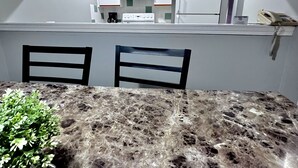 A dining area with a marble table and two chairs, a small plant on the table, and a kitchen visible through an open door in the background. - Two-Bedroom Apartment 131 - Private Entrance - Self Check In (BL-RES-12552) (Canmore)